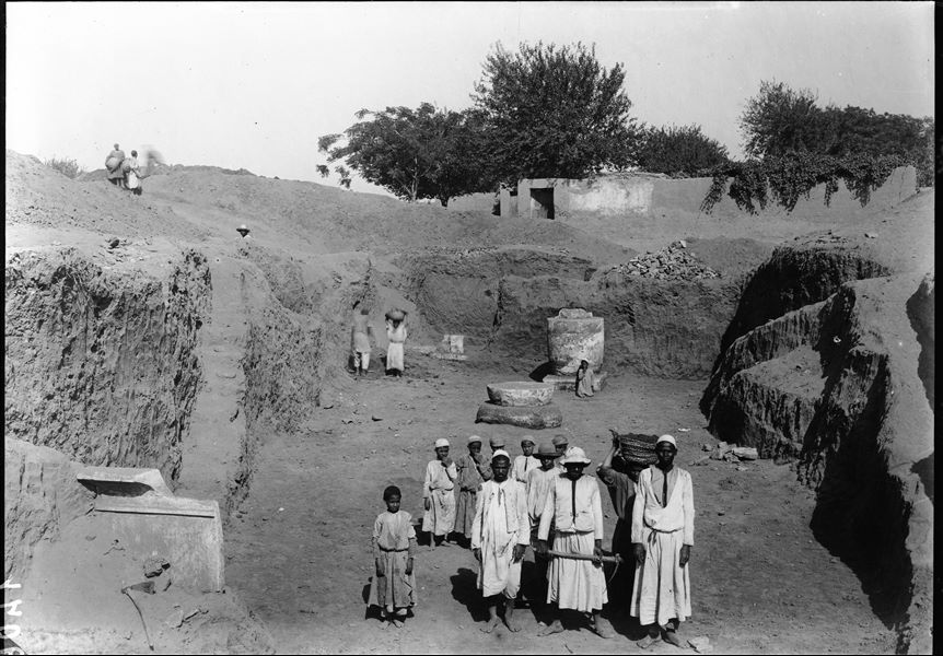 Trench in kom, with “late period” columns. In the background, Arabic houses also near kom. Schiaparelli excavations. 