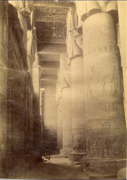La fotografia presenta uno scorcio dell'atrio ipostilo di età romana del tempio di Hathor a Dendera, in cui si apprezzano i capitelli hathorici. Lo scatto è attribuibile ad Antonio Beato.