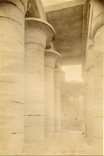 Photograph of the Hypostyle Hall in the Ramesseum, the Funerary Temple of Ramesses II in West Thebes. On the back wall, a scene with Ptah, Amun and Ramesses II is visible (to the right, hidden by the column, is also the figure of the goddess Tefnut). The photograph can be attributed to Antonio Beato.