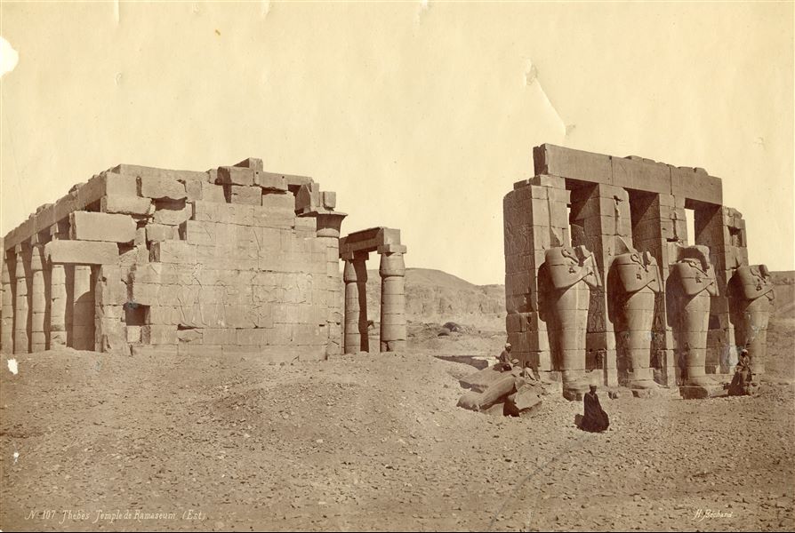 La fotografia mostra una parte del secondo cortile del Ramesseo, in cui si innalzano le statue monumentali osiriache del faraone Ramesse II. La firma dell’autore è in basso a destra. 