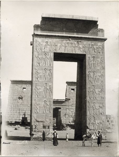 Photograph of the entrance gate to the Karnak Temple Complex built by Ptolemy III Euergetes, behind this stands the Temple of Khonsu. The author's signature, visible at the bottom left is written backwards. 