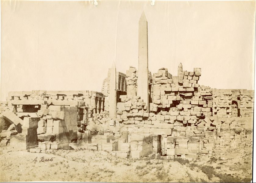 View of the western wing of the Karnak Temple Complex, from the central courtyard on which the Middle Kingdom temple was founded. Among the rubble stand the obelisks of Hatshepsut (centre) and Tuthmosis I (left), and behind them the impressive Great Hypostyle Hall of Pharaoh Seti I. The structures in the foreground correspond to the chapels of Hatshepsut and the sanctuary for the sacred boat of Pharaoh Philip Arrhidaeus (left), Alexander the Great's half-brother and his successor. The author's signature is visible at the bottom left. 