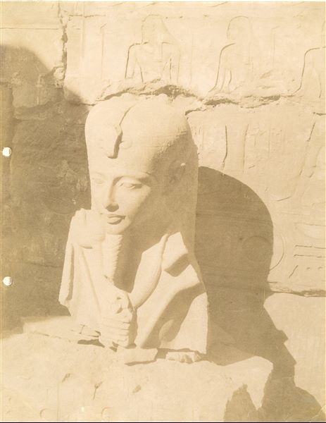 The photograph shows the fragmentary bust of a statue of the god Khonsu depicted in the likeness of Tutankhamun, found in the Karnak Temple Complex. Thanks to the discovery of additional fragments in the 1904 Legrain excavations, the sculpture was later re-assembled and is now in the Egyptian Museum in Cairo (Cairo CG 39488). 