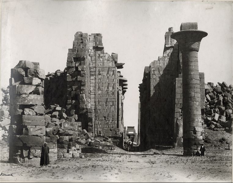 Veduta assiale centrale, che attraversa il II pilone e la Grande Sala Ipostila del complesso templare di Amon a Karnak. A destra, l’unica colonna rimasta del chiosco del faraone Taharqa (XXV dinastia, detta “etiope”). Lungo l’asse centrale si intravede, in fondo a destra, l’obelisco ancora eretto di Thutmosi I. In basso al centro si trova la firma dell’autore.