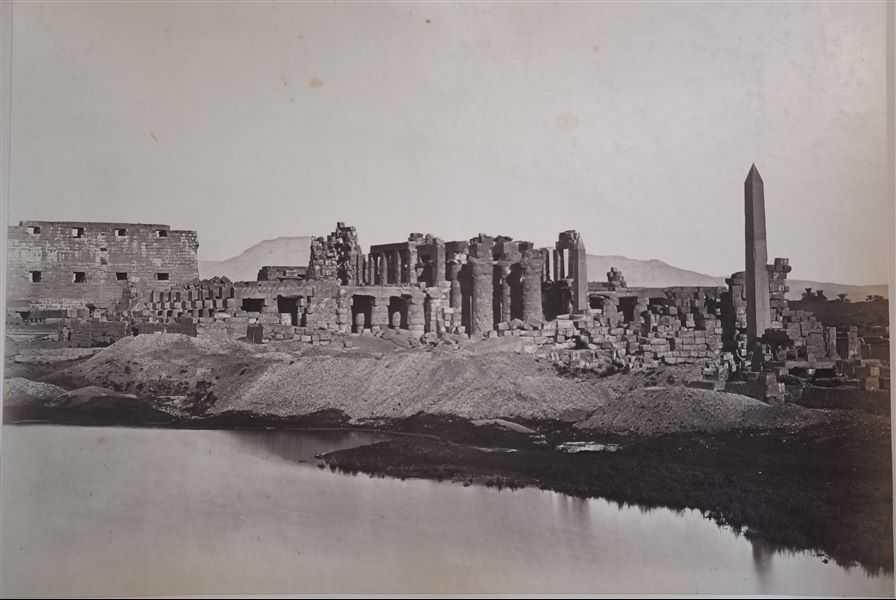 General view of the Karnak Temple Complex, photographed from the Sacred Lake, in the direction of the Great Hypostyle Hall and the first pylon. In the background, the Theban mountain is visible. 