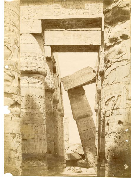 Lo scatto riprende una parte del colonnato laterale della Grande Sala Ipostila del complesso templare di Amon a Karnak, con le colonne papiriformi non ancora del tutto liberate dalla sabbia. In basso si riconosce la firma dell’autore.