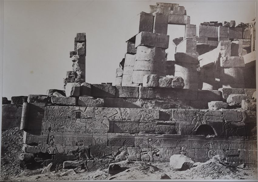 Muro esterno settentrionale della Grande Sala Ipostila del complesso templare di Amon a Karnak. Il faraone Seti I è rappresentato durante le sue campagne in Siria-Palestina. Il livello del suolo copre ancora la parte inferiore del muro. In basso, la firma dell’autore.