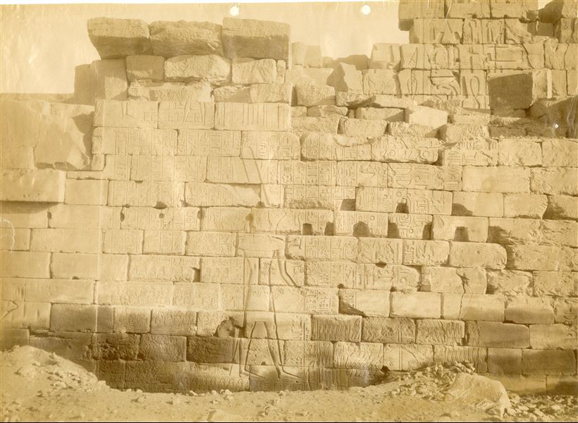 The photograph shows the southern wall of the eastern jamb of the so-called Bubastite Portal, in the Karnak Temple Complex , whose texts celebrate the military campaigns of Pharaoh Sheshonq I, ruler of the 22nd dynasty. The same ruler is depicted in the act of smiting Egypt's enemies. The ground level still covers part of the architecture. The author's signature (which is quite faded) is at the bottom right.   