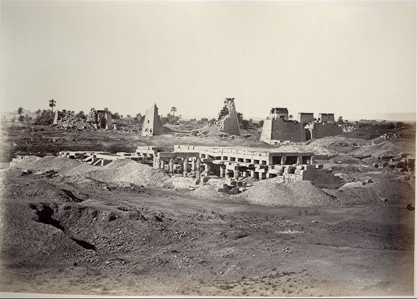 Panorama of the Karnak Temple Complex. In the foreground, the ruins of the Akhmenu (“Festival Hall”), the temple built by ruler Tuthmosis III in the Karnak Temple Complex for his own jubilee, and the “sancta sanctorum” in the Temple of Amun. In the background, from the right, the seventh pylon (very faintly visible, being almost completely destroyed) as well as the eighth, ninth and finally tenth pylons. On the left in the background, the Temple of Luxor is visible. The author's signature can be found at the bottom right. 