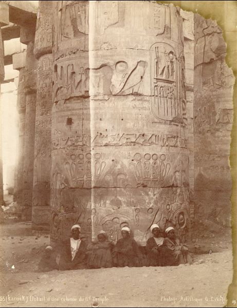 The photograph depicts six young Egyptians in front of a column in the Great Hypostyle Hall of the Karnak Temple Complex, with the cartouche of Pharaoh Ramessess II. The author’s signature is at the bottom.  