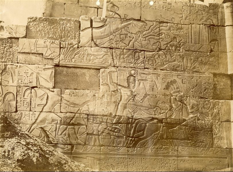 The image depicts some battle scenes of Pharaoh Seti I on the outer wall, north side, of the Great Hypostyle Hall in the Karnak Temple Complex. The author's signature is visible at the bottom left. 