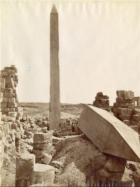 Lo scatto riprende i due obelischi di Hatshepsut nei pressi della Sala Wadjet del faraone Thutmosi I nel Tempio di Amon a Karnak, uno ancora intatto, l'altro, in primo piano, con la cuspide a terra. Un egiziano siede alla base del monumento in secondo piano. Firma e presumibilmente data sono apposte in basso a sinistra.