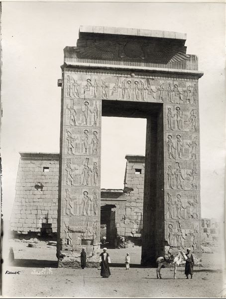 Fotografia del portale di ingresso del complesso templare di Amon a Karnak costruito da Tolomeo III Evergete, dietro il quale si erge il tempio di Khonsu. La firma dell’autore, posta in basso a sinistra, è scritta al contrario.