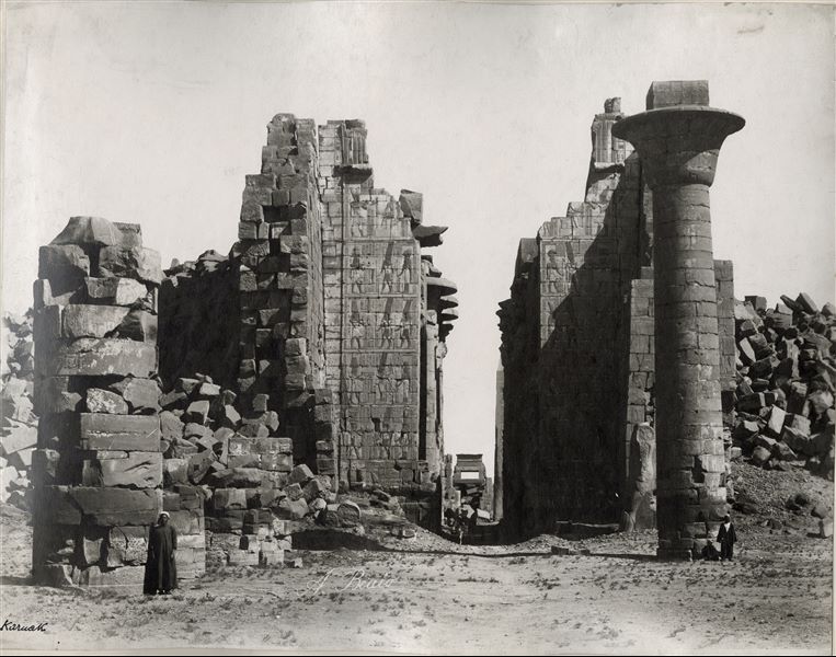 Central axial view through the second pylon and the Great Hypostyle Hall of the Karnak Temple Complex. On the right, the only remaining column of the kiosk of Pharaoh Taharqa (25th dynasty, called the "Ethiopian" Dynasty). Along the central axis, at the bottom right is the still standing obelisk of Tuthmosis I. The author's signature is visible at the bottom centre.   