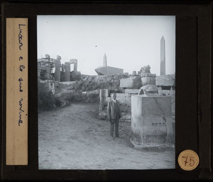 Giovanni Marro si fa fotografare fra le rovine del complesso templare di Amon a Karnak, vicino all’obelisco caduto della regina Hatshepsut. A sinistra, la Sala Ipostila.