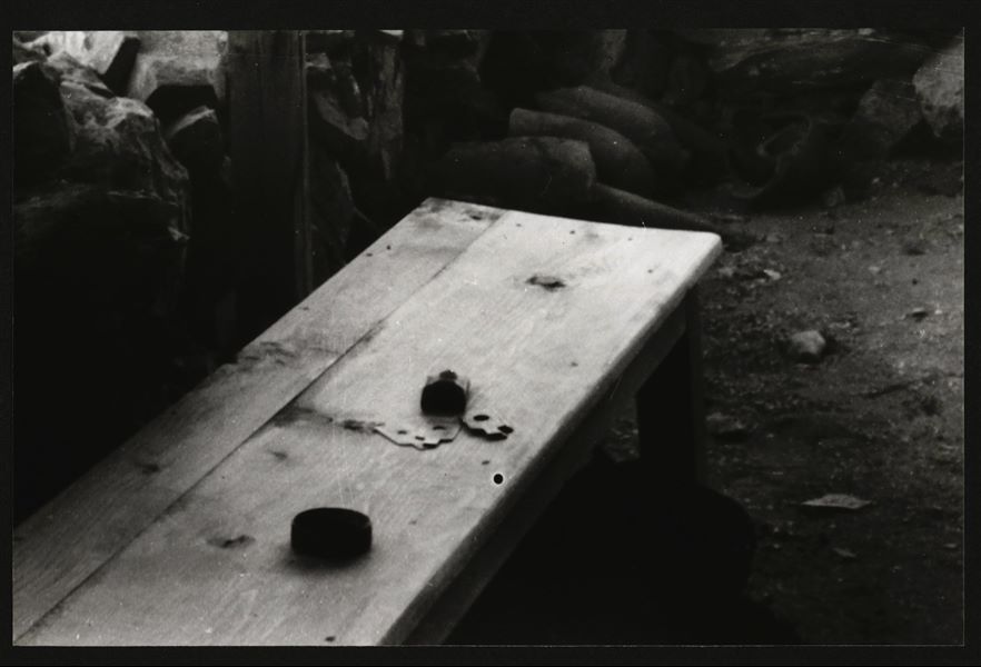 Fotografia all'interno della veranda di una piccola costruzione in mattoni nell'accampamento della MIssione Archeologica Italiana nel sito di Deir el-Medina. Sulla panca sono posti alcuni strumenti fotografici, tra cui un copri-obiettivo e almeno cinque diaframmi. Scavi Schiaparelli