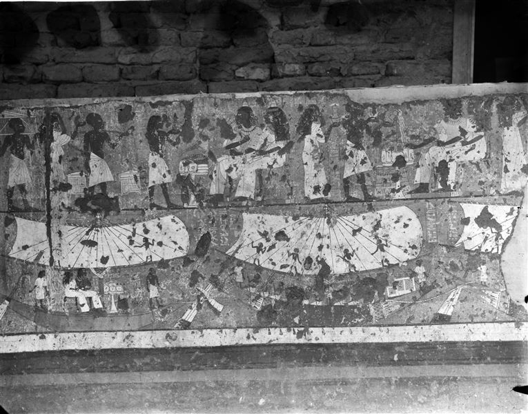 Left sidewall from the chapel of Maya, displaying the central and lower registers. The former shows an offering scene in front of Maya and Tamit whereas the latter displays three sail boats. Photograph taken after the detachment of the painting took place. Here the painting is resting against a small brick structure in the camp near the Valley of the Queens. Schiaparelli excavations.