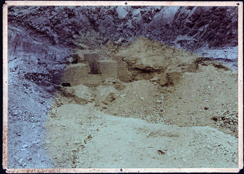 Photograph taken during excavations north of the temple of Hathor and facing a mud-brick structure that sticks out from the sand. Schiaparelli excavations. 