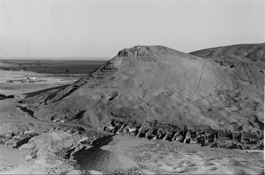 Veduta generale dell’area di Deir el-Medina. La foto è stata scattata dalla montagna a occidente, in basso si vedono le prime case del villaggio con, a sinistra, il tempio della dea Hathor. Di fronte la montagna orientale che delimita il sito, sulla sinistra si intravedono spuntare le rovine dei magazzini del Ramesseo; sullo sfondo la pianura coltivata fino a raggiungere il Nilo. Scavi Schiaparelli. 
