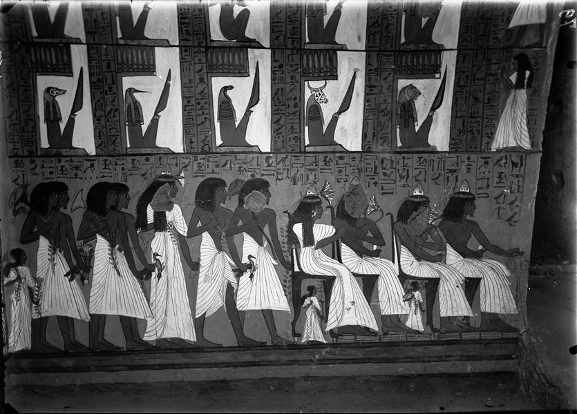 South wall, east side (right) from the tomb of Sennedjem (TT1). In the upper register (divided into two sub-registers), Sennedjem and Iyneferti stand before the ten guardians of the portals (from the right: numbers 1, 3, 5, 7 and 9 in the top register, and 2, 4, 6, 8 and 10 in the bottom register) that they must pass through. This scene is taken from Spells 145 and 146 of the Book of the Dead. In the lower register, a funerary banquet with relatives. 