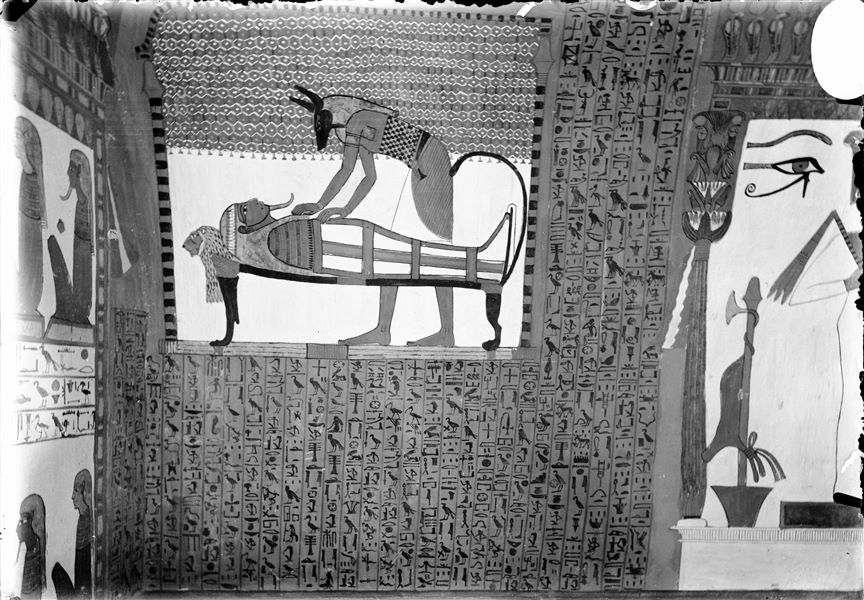 North wall (back) from the tomb of Sennedjem (TT1). The god Anubis is performing the embalming ritual on the mummy of the deceased. Around him is the text from Spell 1 of the Book of the Dead. On the right, the god Osiris inside a shrine. 