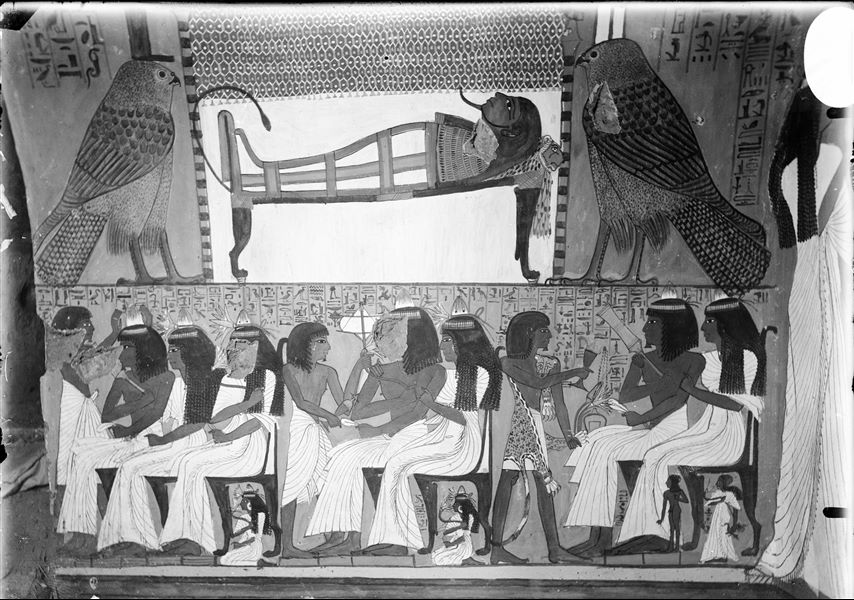 South wall, west side (left) of the entrance to the tomb of Sennedjem (TT1). In the upper register, the deceased is resting on a small bed between the goddesses Isis (left) and Nephtys (right) in the form of falcons. The register below displays some relatives, including his son Bunakhtef, dressed as a sem-priest wearing a leopard skin and presenting a libation to the deceased couple, Sennedjem and Iyneferti.   