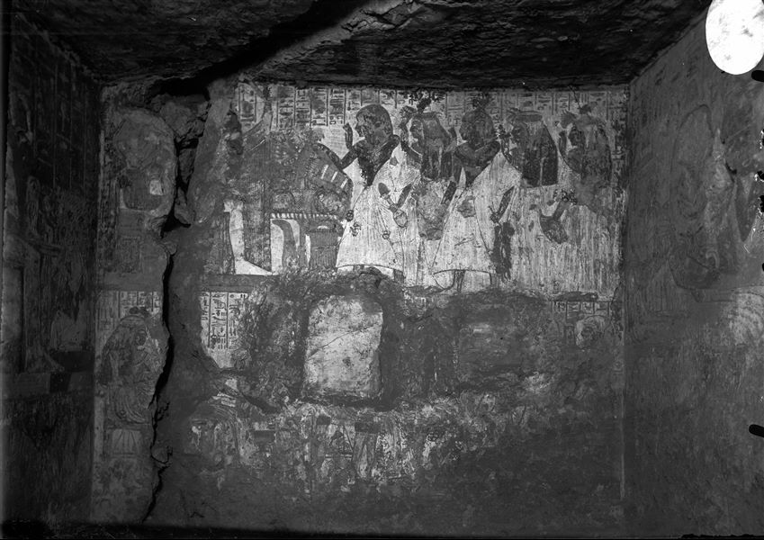 North wall from the tomb of Qen (TT 4). Two registers are visible, in the first one the deceased is depicted with his family members while making offerings to the gods Ptah and Maat. The second register (lower one), is difficult to interpret, however, visible in the centre of the wall is the spot where a stele once stood. 