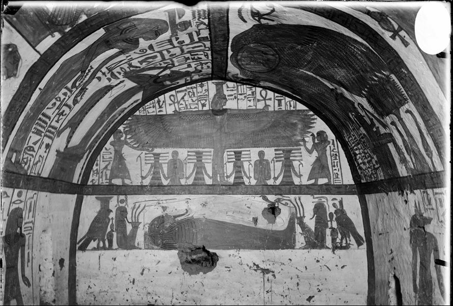 North wall (at the back) from the burial chamber of the tomb of Neferabet (TT 5).  The upper register shows the winged goddess Nephthys, being worshipped by the deceased and his family. The lower register shows the mummy of the deceased, with the goddesses Nephthys (left) and the Isis (right) in the form of falcons on either side of Neferabet. Next to the goddesses are two divine figures (HxH and Dt). 