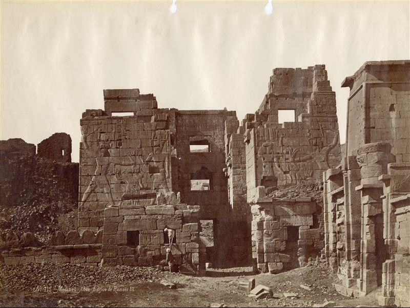 La fotografia mostra l'accesso al tempio funerario di Ramesse III a Medinet Habu: il portale presenta le caratteristiche architettoniche del migdol, una fortezza siriana. In basso a destra la firma dell’autore.