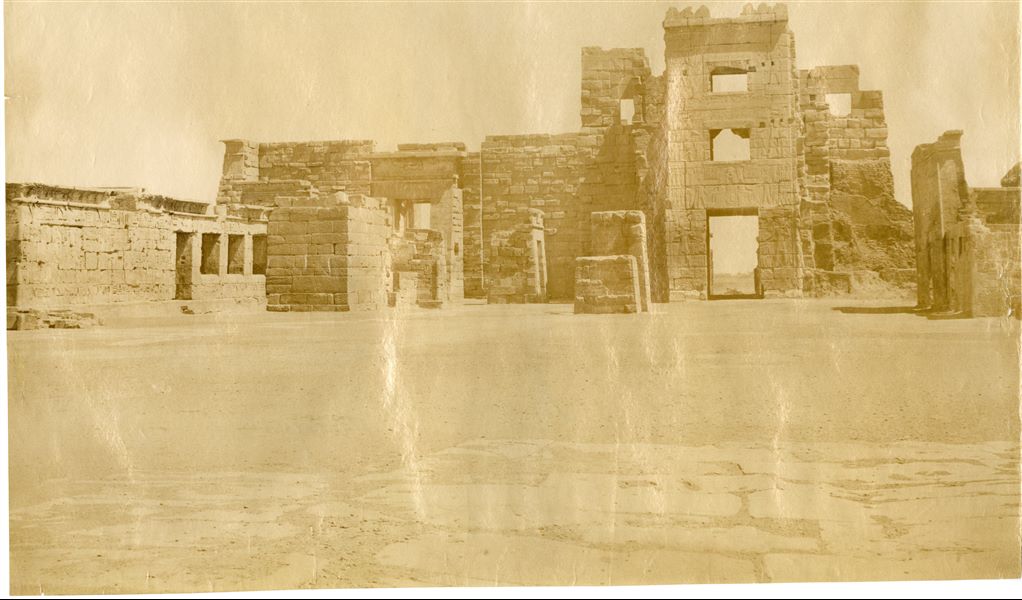 The photograph shows a view from inside the entrance gate of the Temple of Ramesses III at Medinet Habu, a structure that reflects a migdol, a fortress of syrian origin. Photograph taken from the temple’s first pylon. The author's mirrored signature (almost completely erased) is on the left. 
