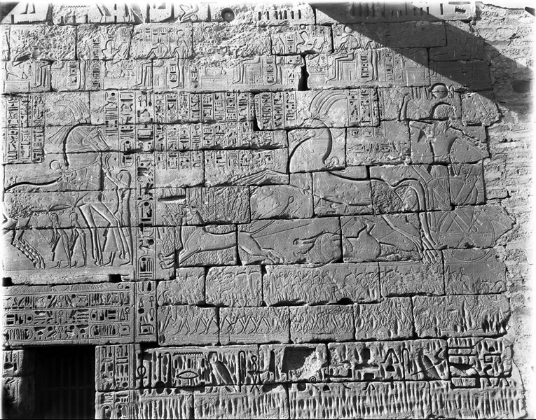 North wall, external facade from the temple of Ramesses III, near the access to the second court. In the main scene, Ramesses III is shown hunting lions.