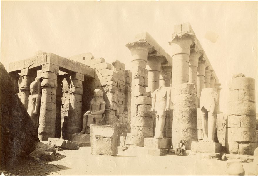 La fotografia mostra una veduta delle rovine del tempio di Amon a Luxor. La firma di Beato, bianca e quasi illeggibile, è riportata con grafia speculare in basso a sinistra.  