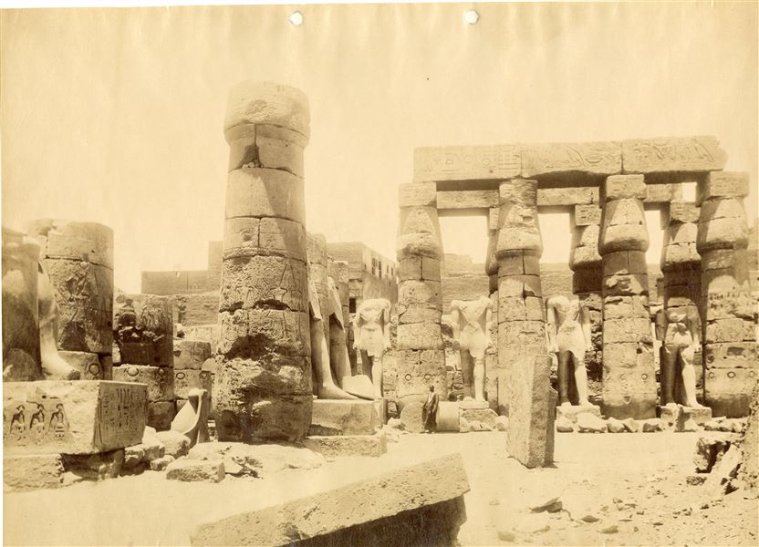 Veduta dell'accesso al colonnato processionale di Amenhotep III, fotografata dall'interno del grande cortile di Ramesse II nel tempio di Amon a Luxor. La presenza di due persone mostra la monumentalità delle statue e delle strutture architettoniche ancora presenti. 