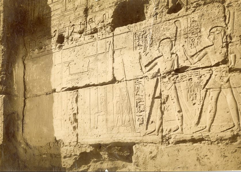 La fotografia mostra un dettaglio della decorazione a rilievo dal tempio di Amon a Luxor, nel quale si vedono i due principi ramessidi Amon-her-khepeshef e Ramesse a destra, di fronte al pilone del tempio voluto dal loro padre Ramesse II. La firma dell'autore è apposta in basso al centro.  