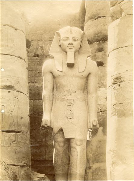 Photograph of a colossal statue of Pharaoh Ramesses II, still standing in the Great Court built by the same pharaoh, in the Temple of Luxor. The photograph can probably be attributed to Antonio Beato. 