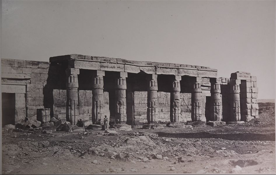 La fotografia mostra una veduta del colonnato e dell’ingresso del Tempio del faraone Seti I a Qurna, davanti a cui posano alcuni egiziani. 