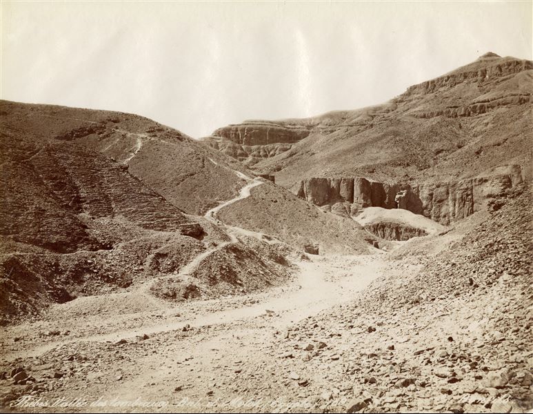 Nell’immagine è rappresentato il panorama desertico della montagna tebana sulla riva Ovest del Nilo, e il sentiero che conduce all’ingresso della Valle dei Re. In basso, la firma dell’autore.  
