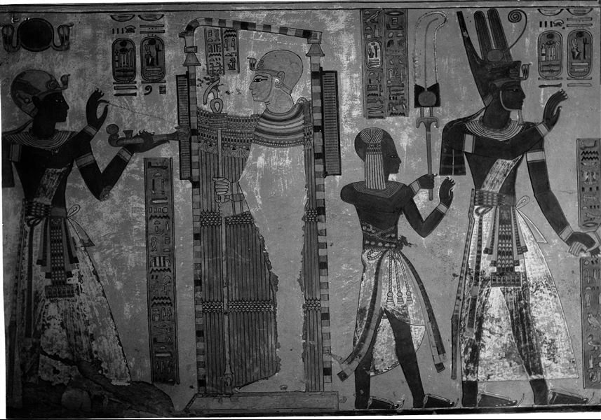 East wall (left) from the antechamber of the tomb of Amonherkhepeshef (QV55). In this photograph two scenes can be observed. In the first one, Ramesses III holding an incense-burner worships the god Ptah who is inside a shrine. In the second scene Ramesses III is holding the hand of the god Ptah-Tatanen, of which only his hand is visible in this image. Behind Ramesses III is his son Amonherkhepeshef. Schiaparelli excavations. 