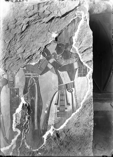 North wall (right of the entrance) from the antechamber of the tomb of Amonherkhepeshef (QV55). The pharaoh Ramesses III is depicted in the act of embracing a female deity, unfortunately not recognizable due to the collapsed plaster at the top of the scene. On the right, the modern door to the tomb entrance is visible. Schiaparelli excavations. 