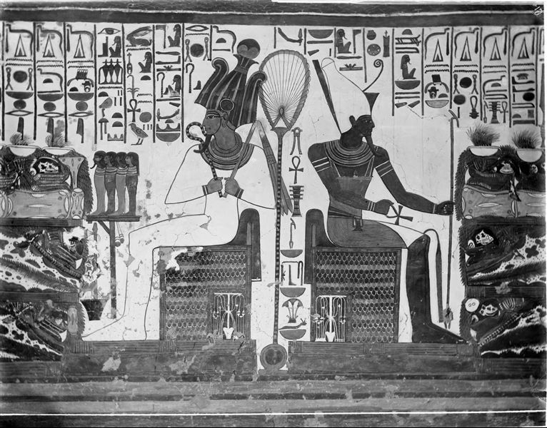 First eastern annex (alcove), east wall, scene 18. Representation of the central area of the wall, where two deities are seated; on one side Osiris, on the other Atum. They are positioned symmetrically and receive a pile of offerings from Nefertari. Neither Nefertari or the offering pile are visible here. 