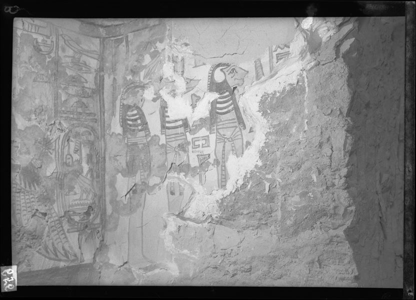 Burial chamber, small niche in the middle of the west wall, scene 32. The image shows the north wall of the niche depicting three mummiform figures, probably Hapy, Anubis and Duamutef, here with the head of a falcon. In recent times, part of the plaster from this wall has collapsed. The back wall (left) shows the winged goddess Nut.