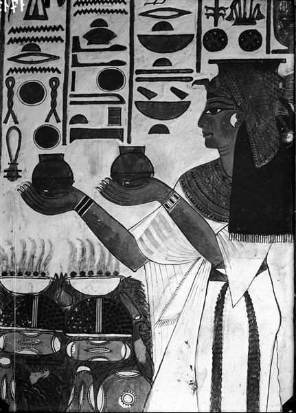 Descending corridor, east wall, scene 23. At the top of the descending corridor, there is a series of deities in the act of receiving offerings from Nefertari. Here she is seen holding two small jars in her hands in front of an offering table.