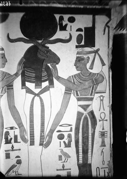 First eastern annex (alcove), west wall, south side, scene 15. A mummiform deity with a ram's head and sun disc - reminiscent of the characteristics of Osiris and Ra - is assisted by the goddesses  Nephthys (left) and Isis (right).