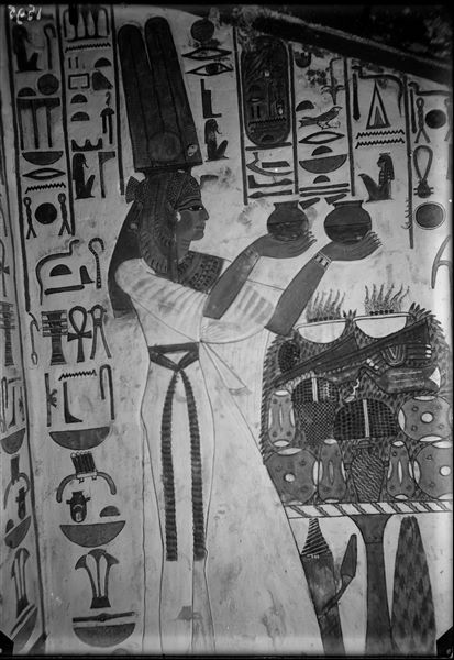 Descending corridor, west wall, scene 22. At the top of the descending corridor, there are three deities in the act of receiving offerings from Nefertari. Here she is seen holding two small jars in her hands in front of an offering table.