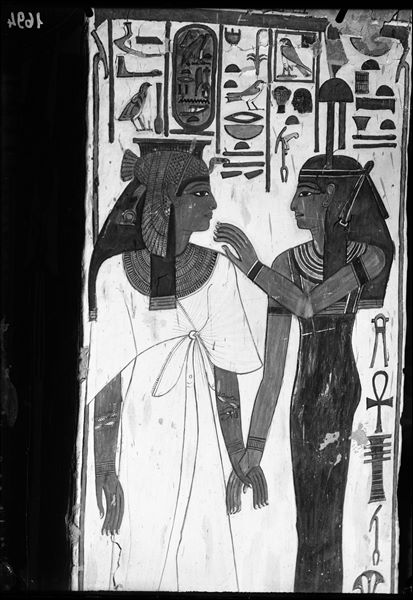 View of pillar B, side c, from the burial chamber. Depicted holding hands: Queen Nefertari on the left and the goddess Hathor on the right, with the emblem representing the West on her head. 