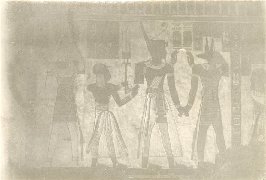 Parete est (sinistra) della sala trasversale della tomba del principe Amenherkhepeshef (QV55). Sono rappresentati sei personaggi, in tre scene distinte. Da sinistra: Ramesse III e Ptah-Tatanen, il giovane Amenherkhepeshef, Ramesse III con Duamutef. L’ultimo a destra, appena visibile, è ancora Amenherkhepeshef. Fotografia molto sbiadita. Scavi Schiaparelli.