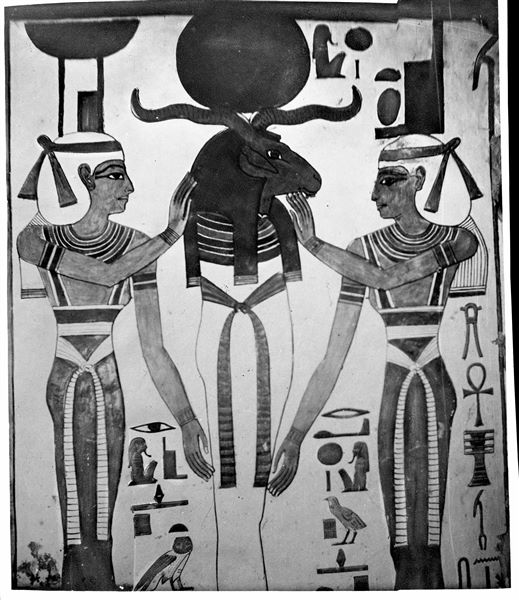 Primo annesso orientale (alcova), parete ovest, lato sud, scena 15. Una divinità mummiforme con testa di ariete e disco solare, che richiama alle caratteristiche di Osiride e di Ra, è assistita dalle dee Neftys (a sinistra) e Iside (a destra).