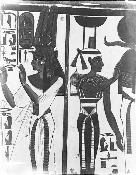 Primo annesso orientale (alcova), parete ovest, lato sud, scene 15 e 16. A sud (sinistra), Nefertari nell’atto di recitare un’invocazione presente nel cap. 148 del Libro dei Morti, a nord (destra), parte della scena 15, la dea Neftys nell’atto di assistere una divinità mummiforme con testa d’ariete e disco solare, caratteristiche di Osiride e Ra.