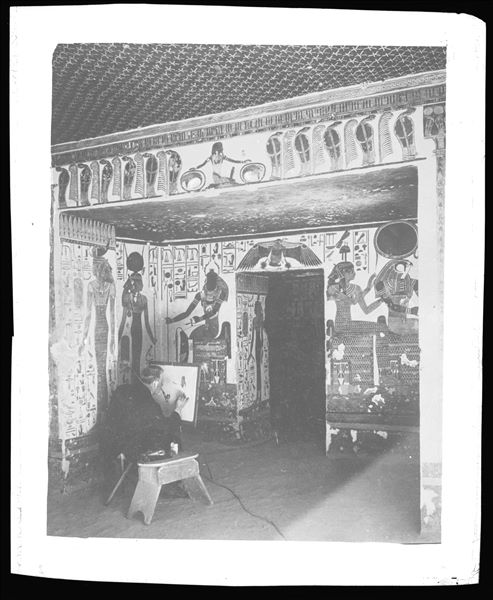 Vestibolo, angolo nord-est, scene 9 e 10. La dea Iside accompagna Nefertari (non visibile in questa fotografia) verso il dio Khepri, presente nella parete est, lato nord, del vestibolo. Al centro vi è l’accesso al primo annesso orientale (alcova). Il disegnatore fotografato non ha un’identità certa.