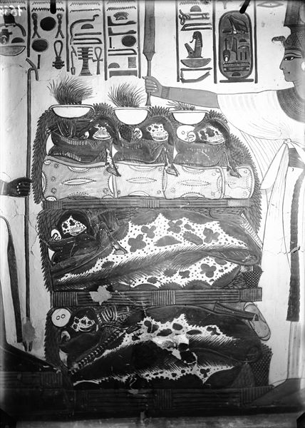 Primo annesso orientale (alcova), parete est, scena 18. Dettaglio del tavolo colmo di offerte rappresentate tra Nefertari e il dio Atum assiso. L’iscrizione soprastante, da una parte rappresenta l’invocazione di Nefertari con le offerte per il dio, dall’altro la risposta benevola del dio.